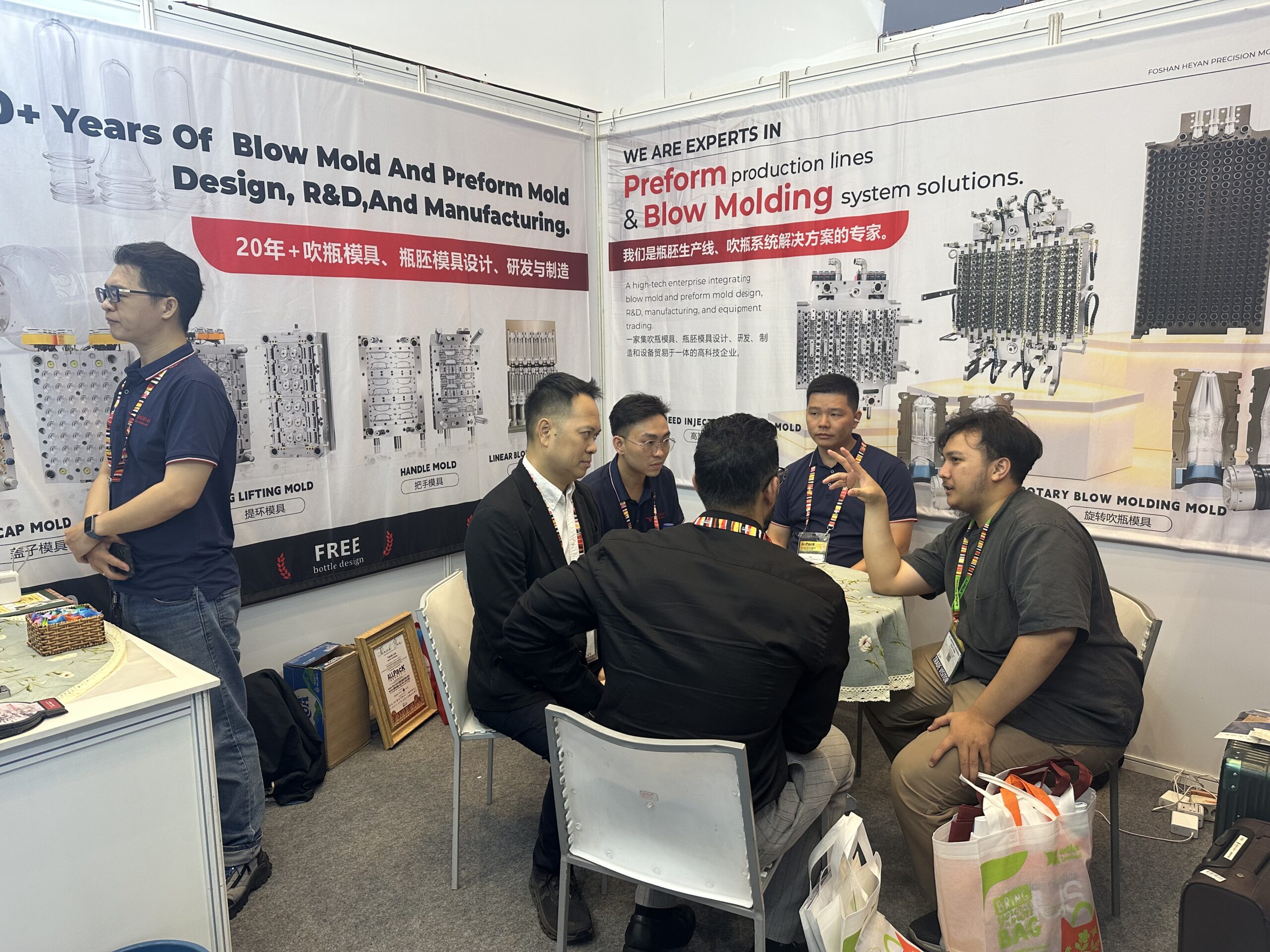 Heyan team discussing PET preform mold specifications with a visitor at ALLPACK Indonesia 2026